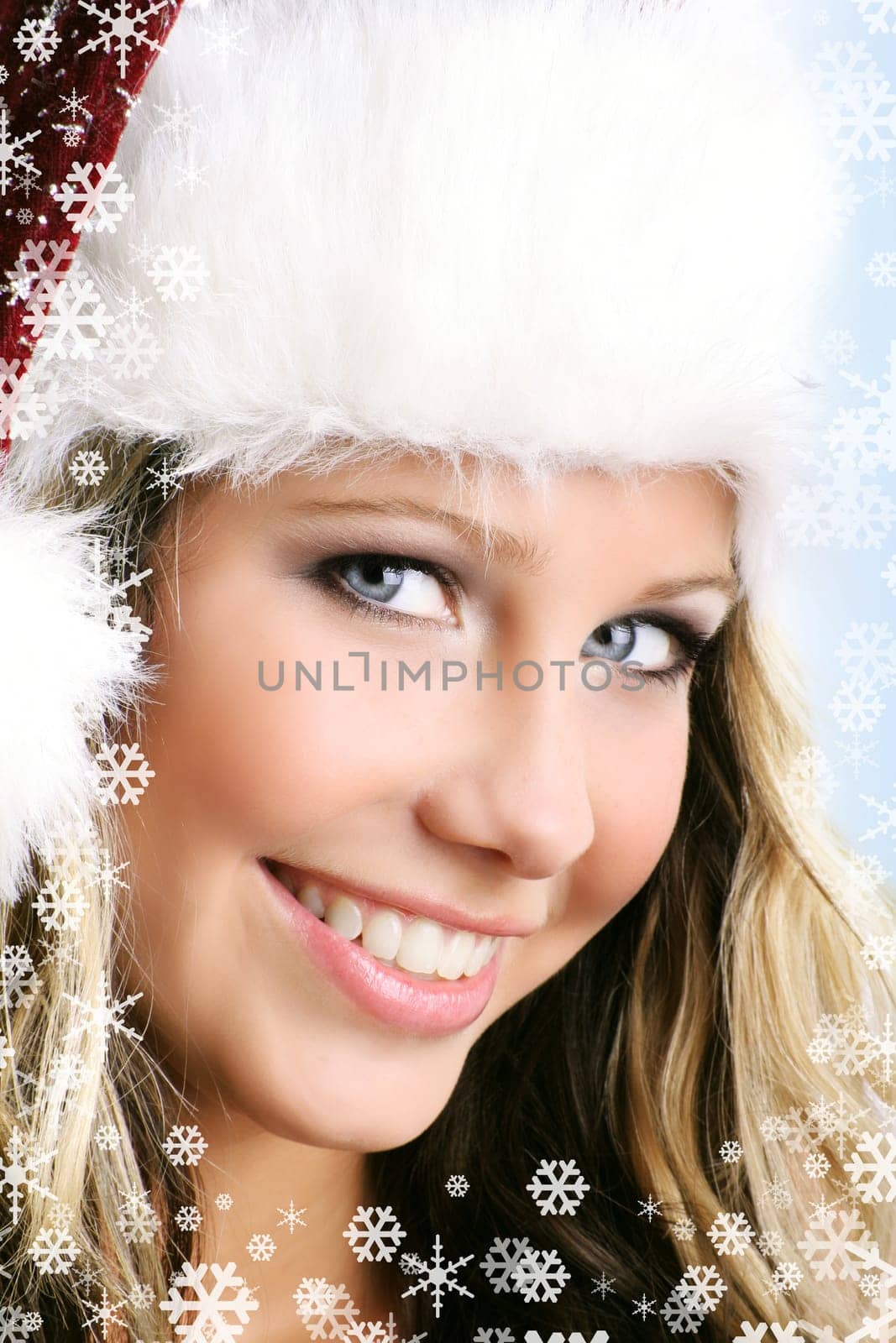winter portrait of a young smiling woman with a christmas cap and snowflakes