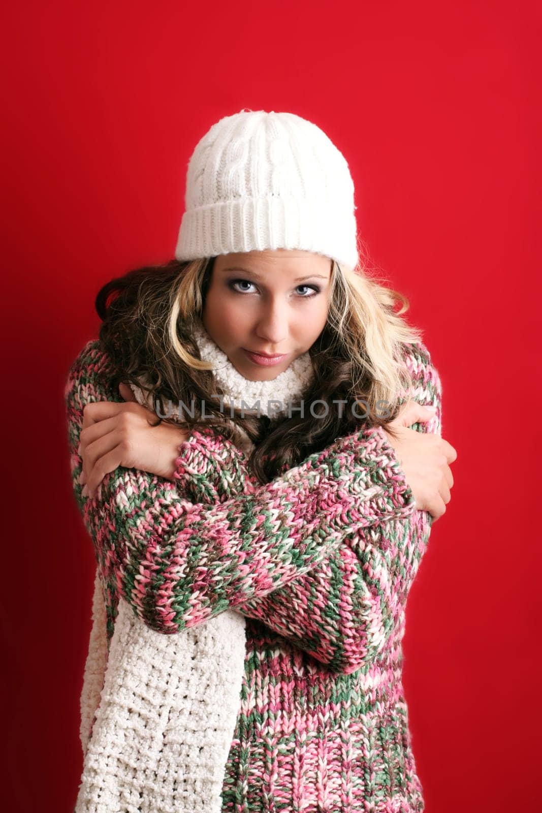 winter portrait of a beautiful young woman is freezing with a cap and a scarf