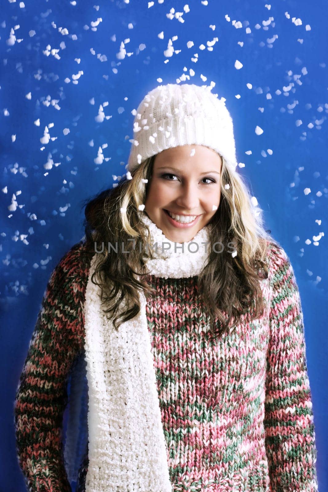 winter portrait of a beautiful woman is freezing with a cap and a scarf and snowflakes