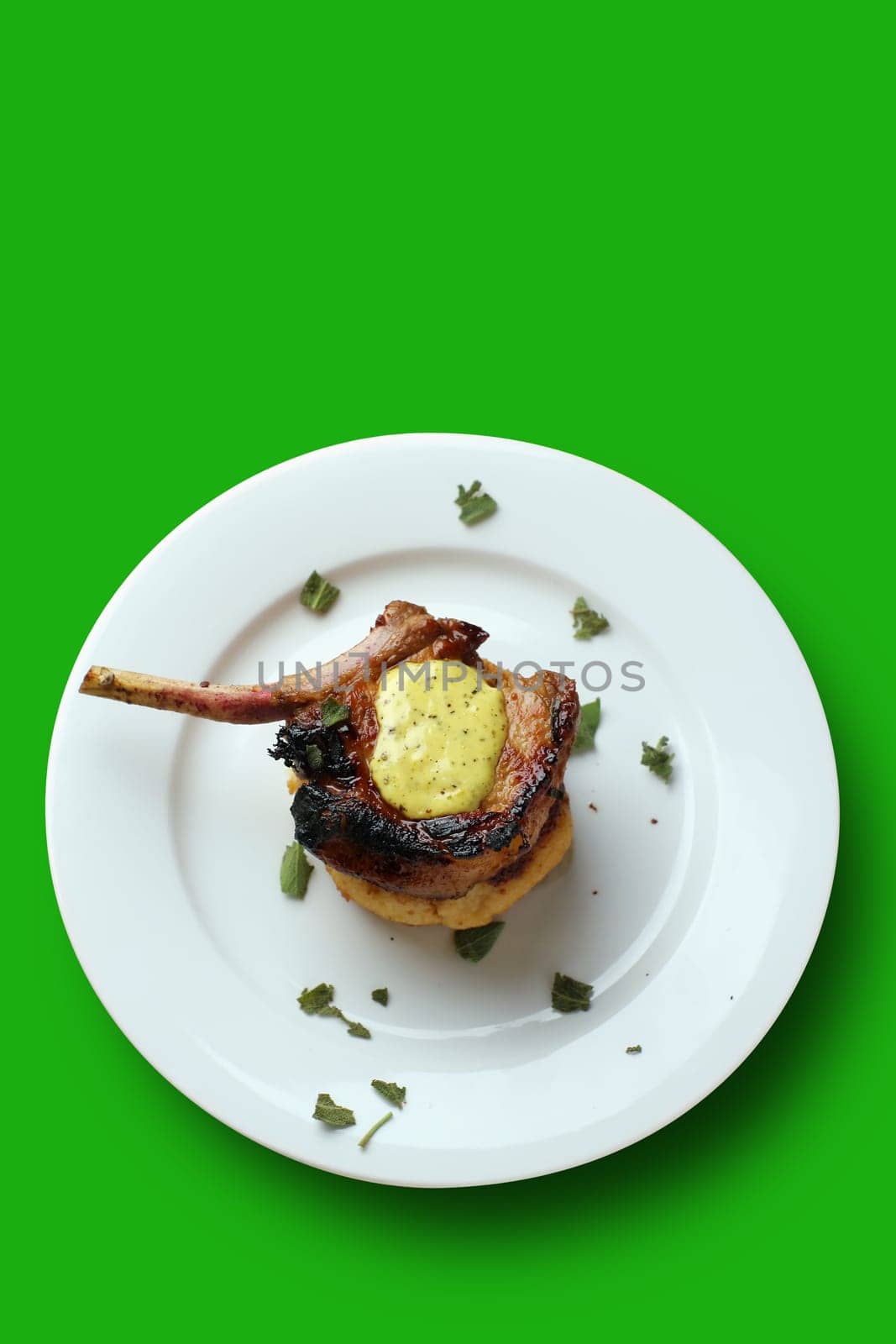 Pan fried pork cutlet on a tomato capsicum cous-cous with lime aioli (lime, olive oil, and egg) coriander garnish. this file has a clipping path as demonstrated by the green background. You can sit this image on any background you choose.