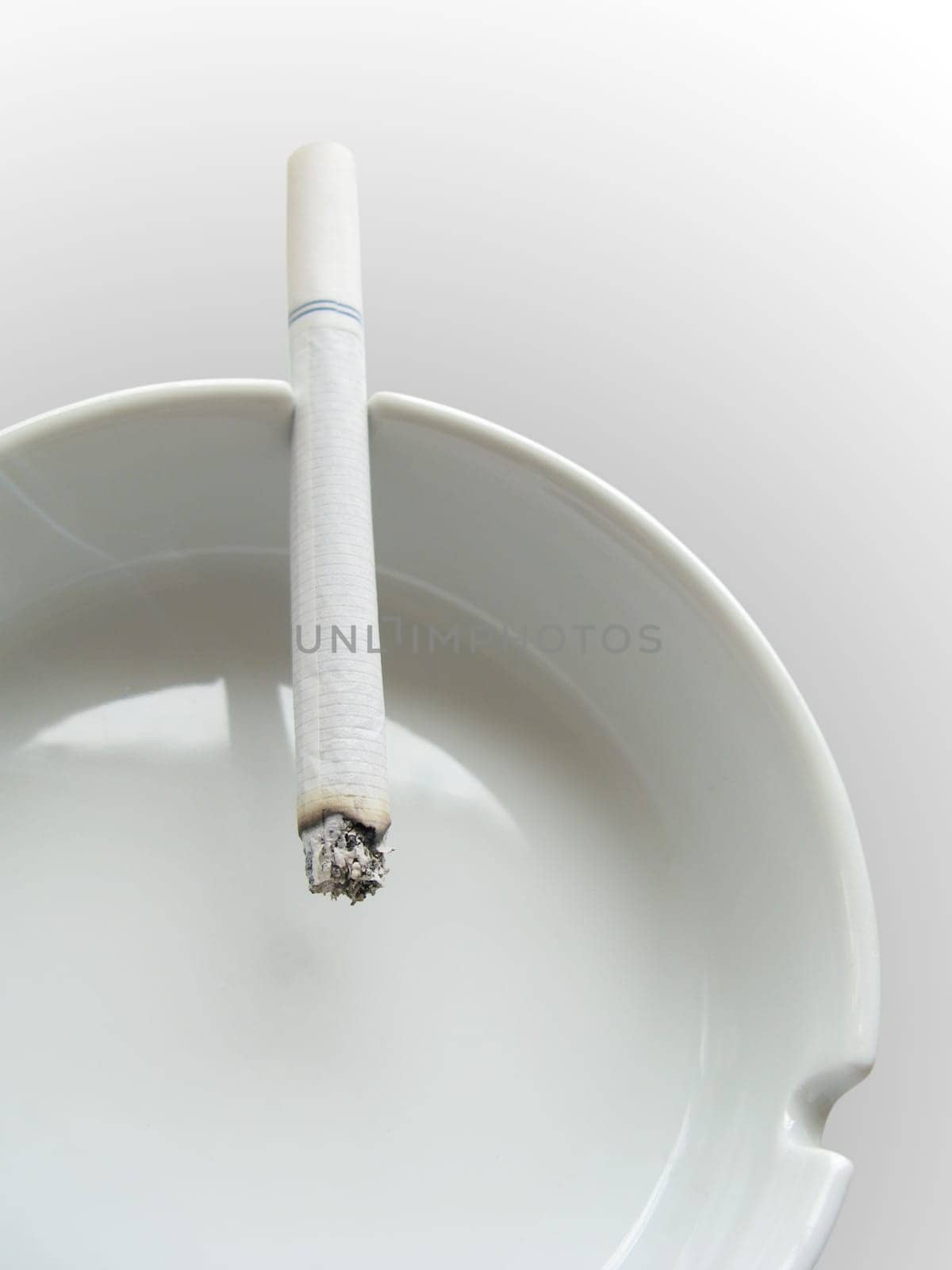 close photo of cigarette and ashtray on white background