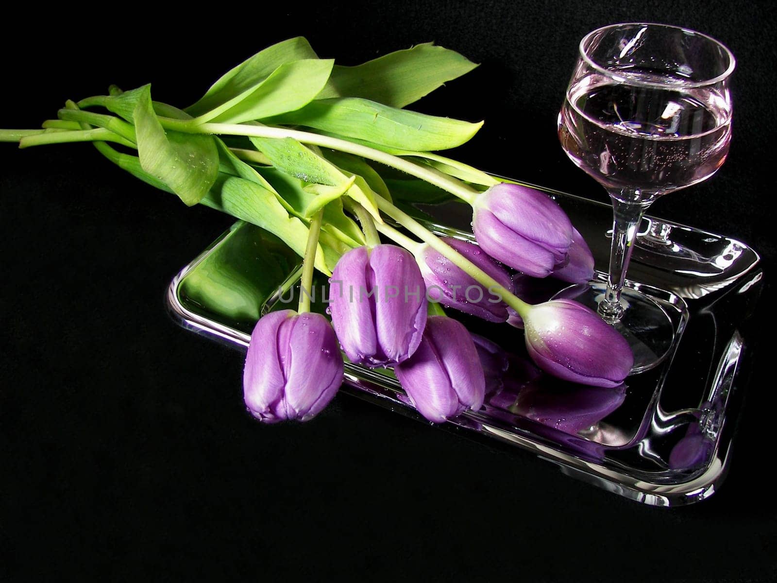 Bouquet of purple tulips on silver platter with wine.