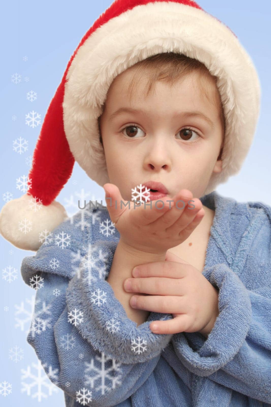 The boy blows on white snowflakes on a hand