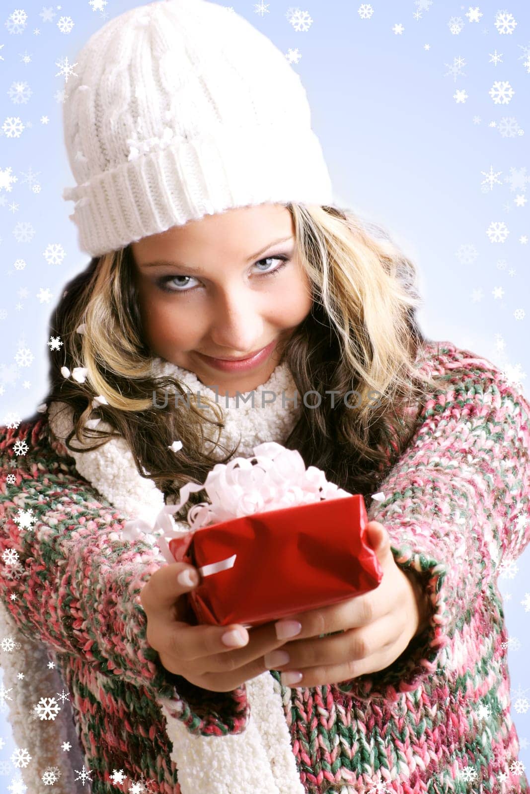 winter portrait of a smiling woman with a gift in her hands and snowflakes