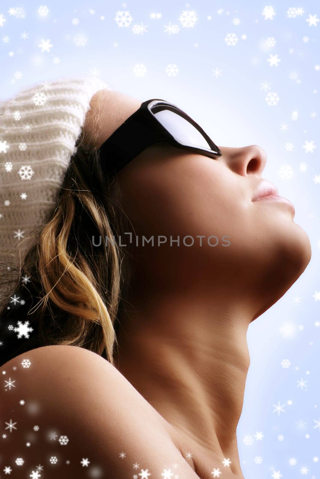 winter portrait of a young beautiful woman with a cap and snowflakes