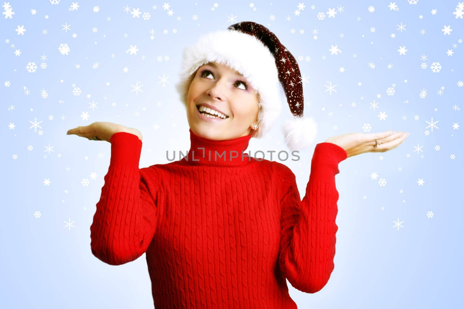 winter portrait of a young smiling woman with a christmas cap and snowflakes