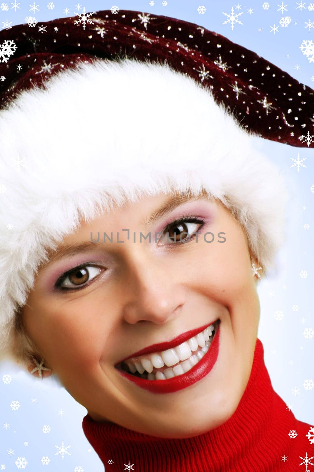 winter portrait of a young smiling woman with a christmas cap and snowflakes