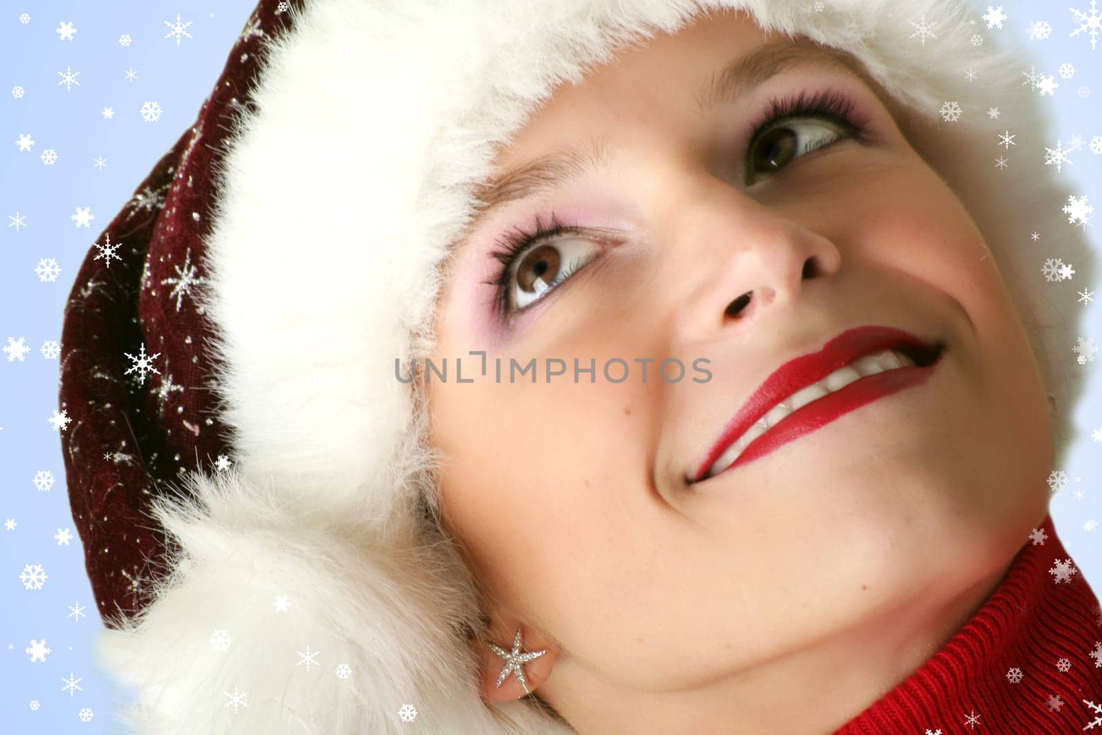 winter portrait of a young smiling woman with a christmas cap and snowflakes
