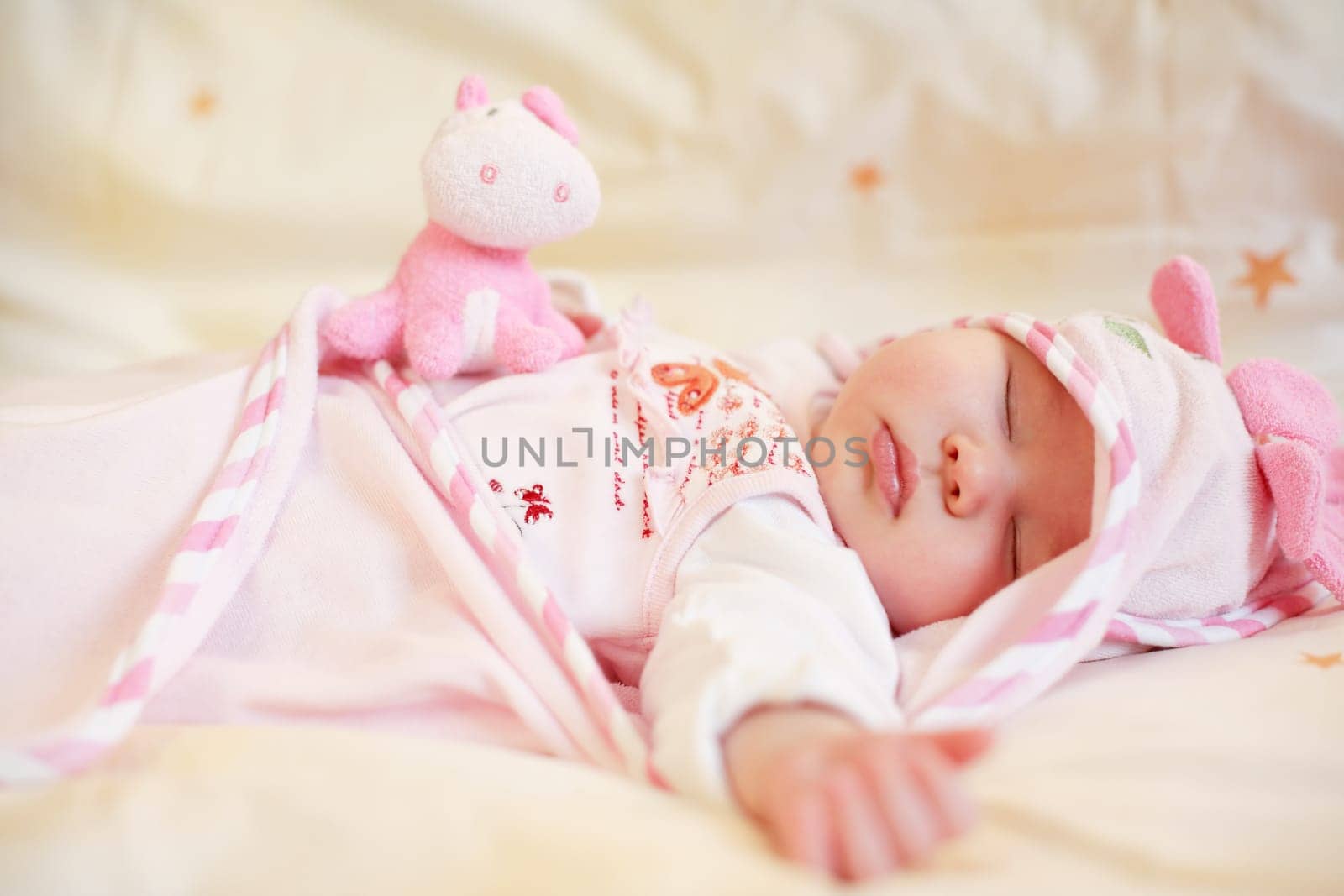 Lying sleeping baby with small teddy bear on bright background