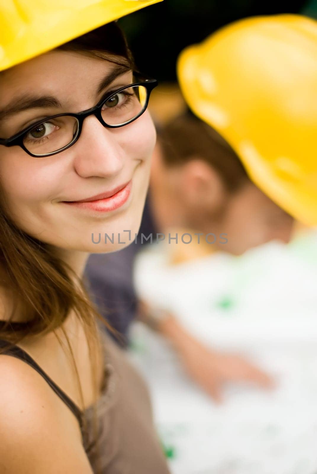 young female smiling architect or builder wearing a yellow hart hat on a construction site