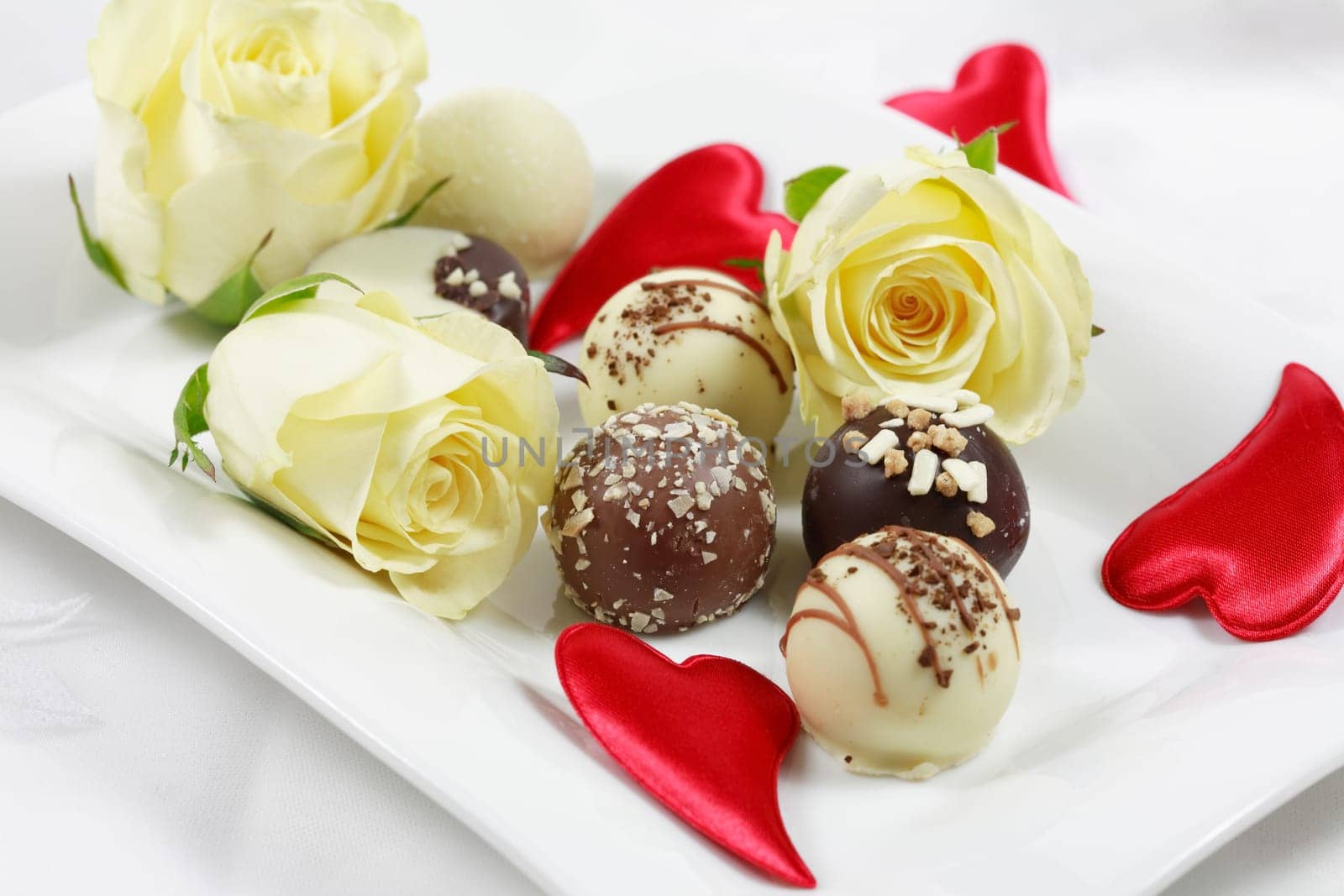 Delicious chocolate pralines with rose on white plate