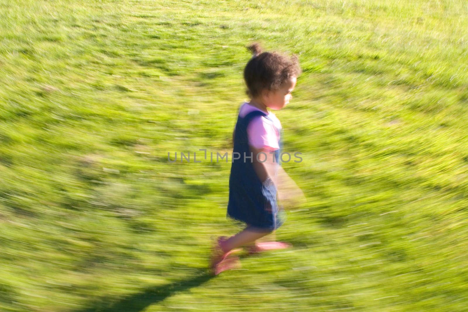 Motion blurred shot of a little girl running in a field