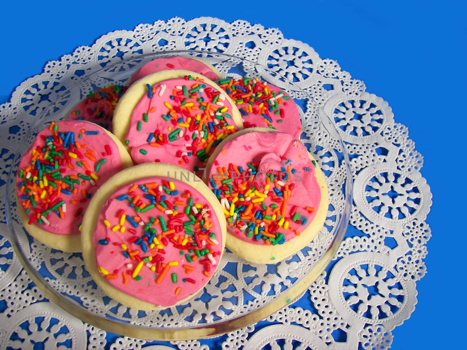Glass plate of cookies on white doily.