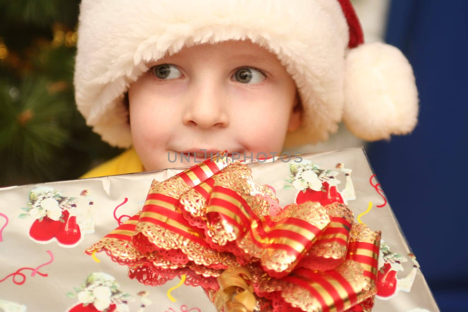 The boy in a New Year's cap and a gift