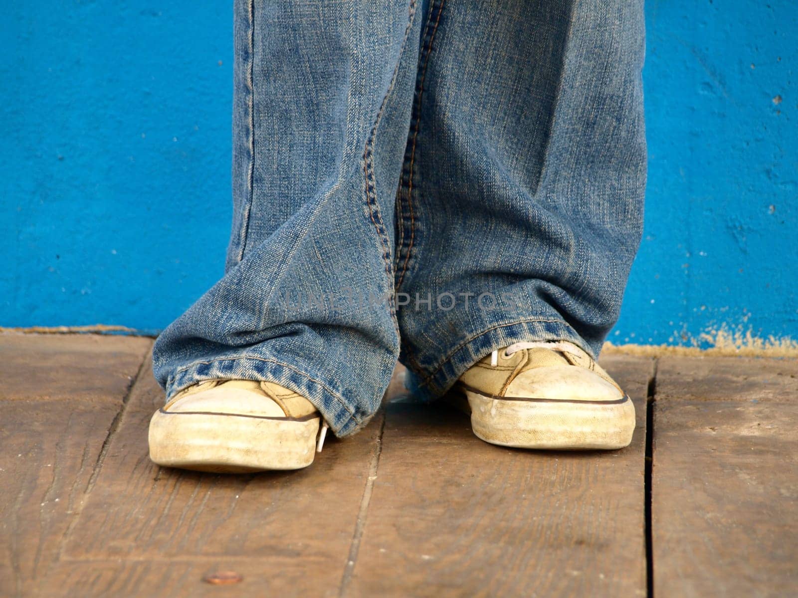Shoes under jeans against blue background