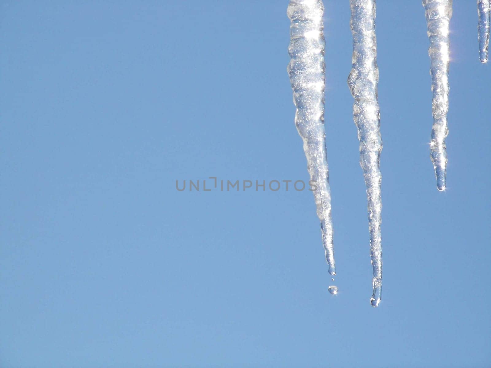 Icicles dripping against a blue winter sky.