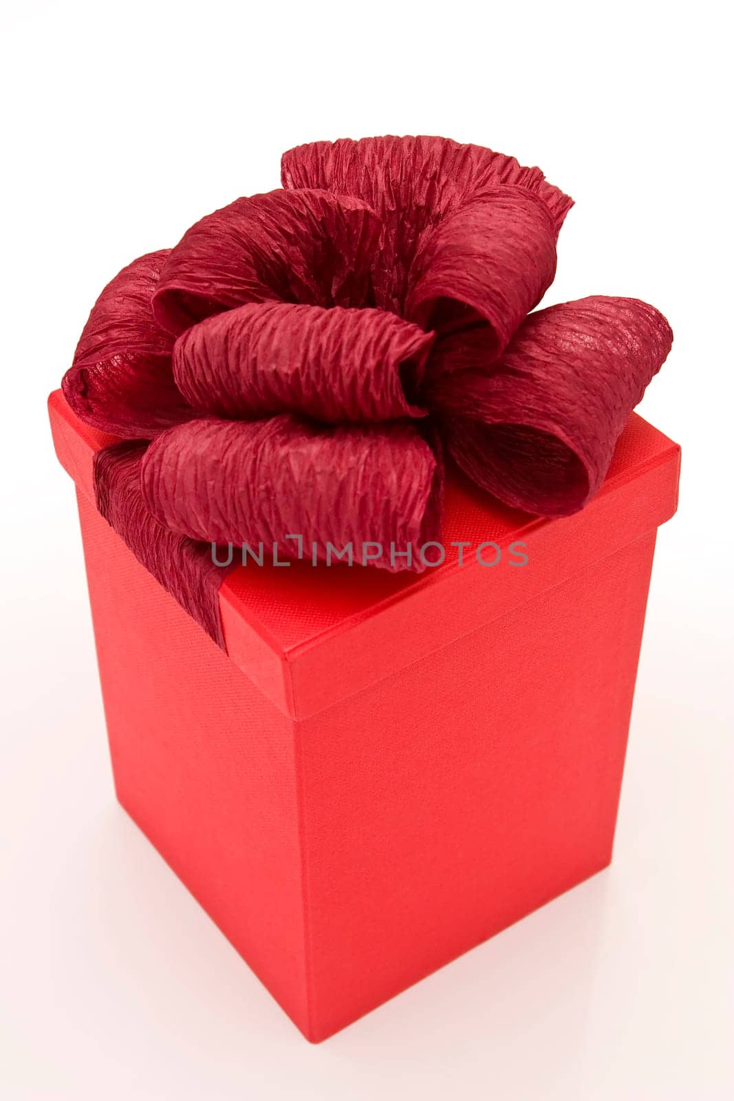 close up photo of red gift box tied with ribbon on white background
