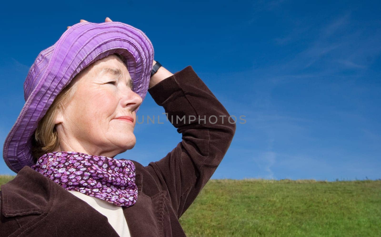 Happy mature woman on the meadow - in her favourite violet hat :-)