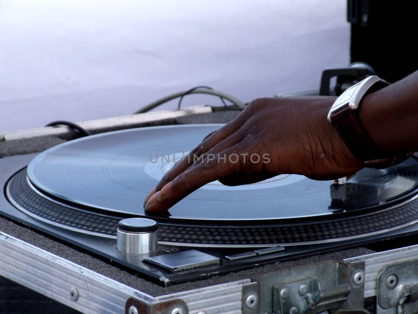 Close-up hotograph of a Black young adult male DJ's hand spinning vinyl record