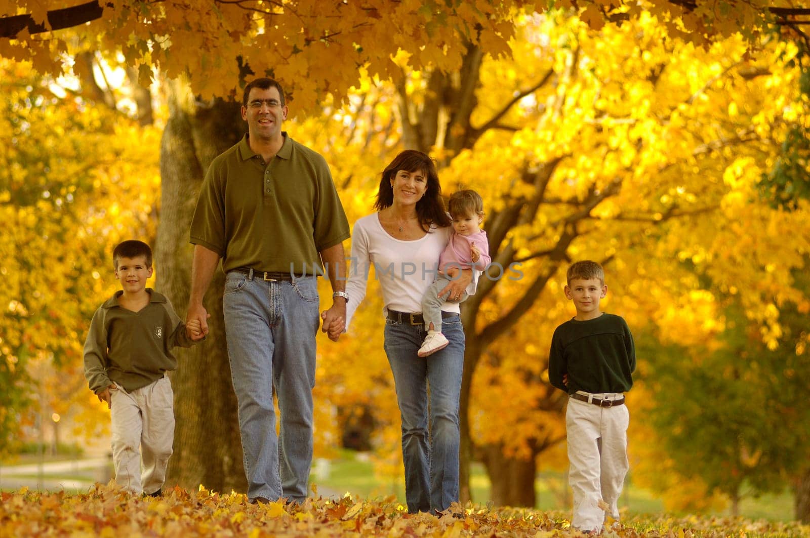a happy family walking through colorful leaves