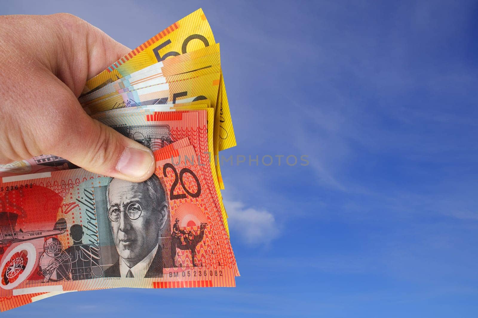 Holding Australian money clear blue sky