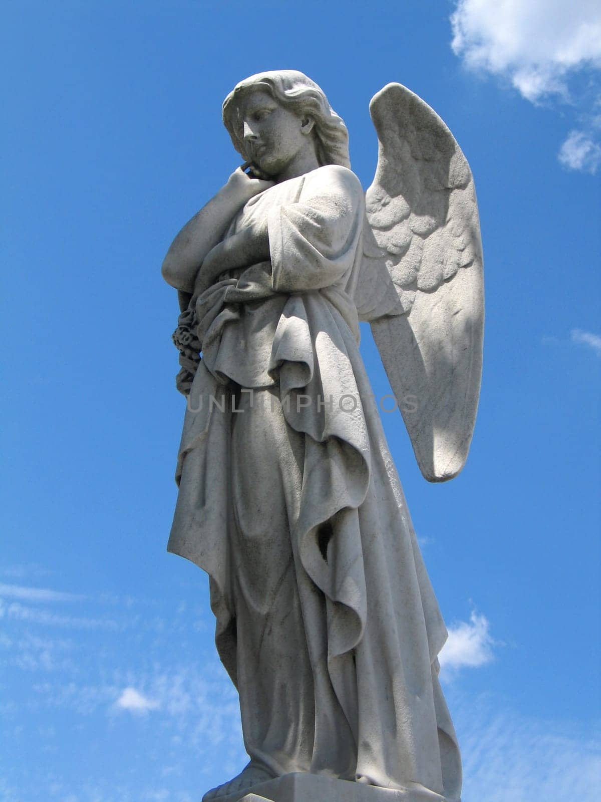 detail of winged angel statue against blue sky
