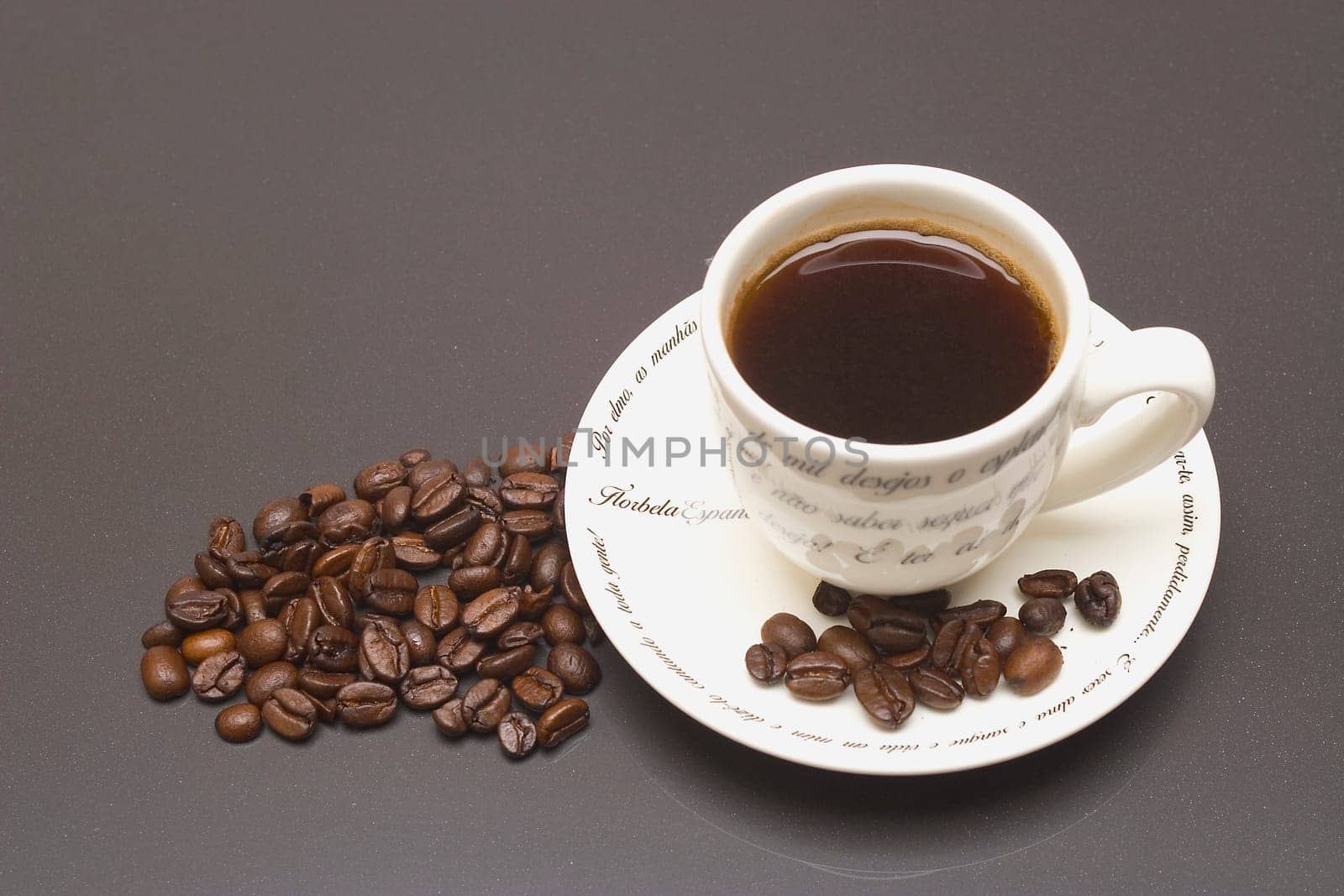 A cup of black coffee and beans on a saucer