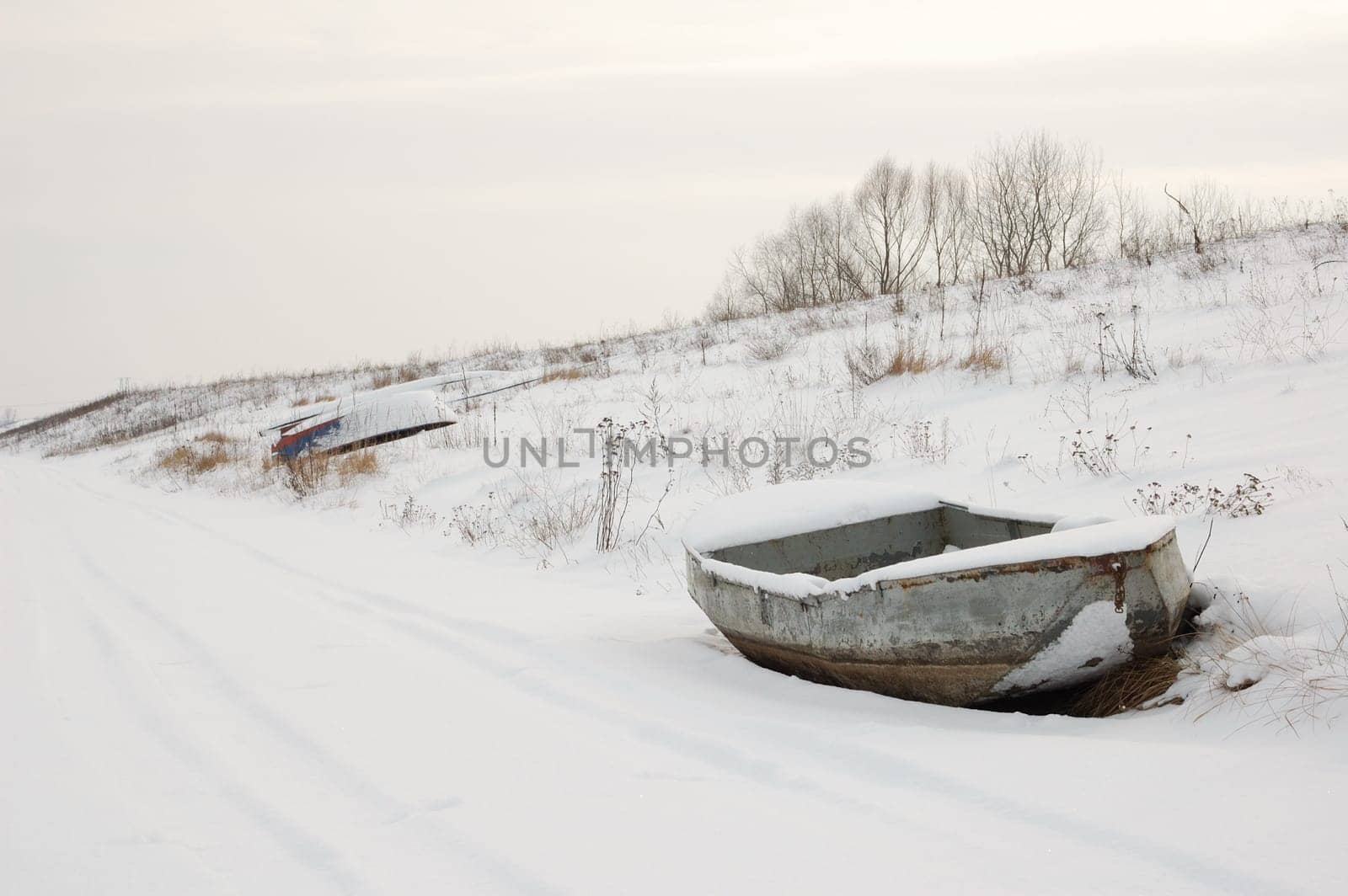 Boat in snow on shore, with visible trail