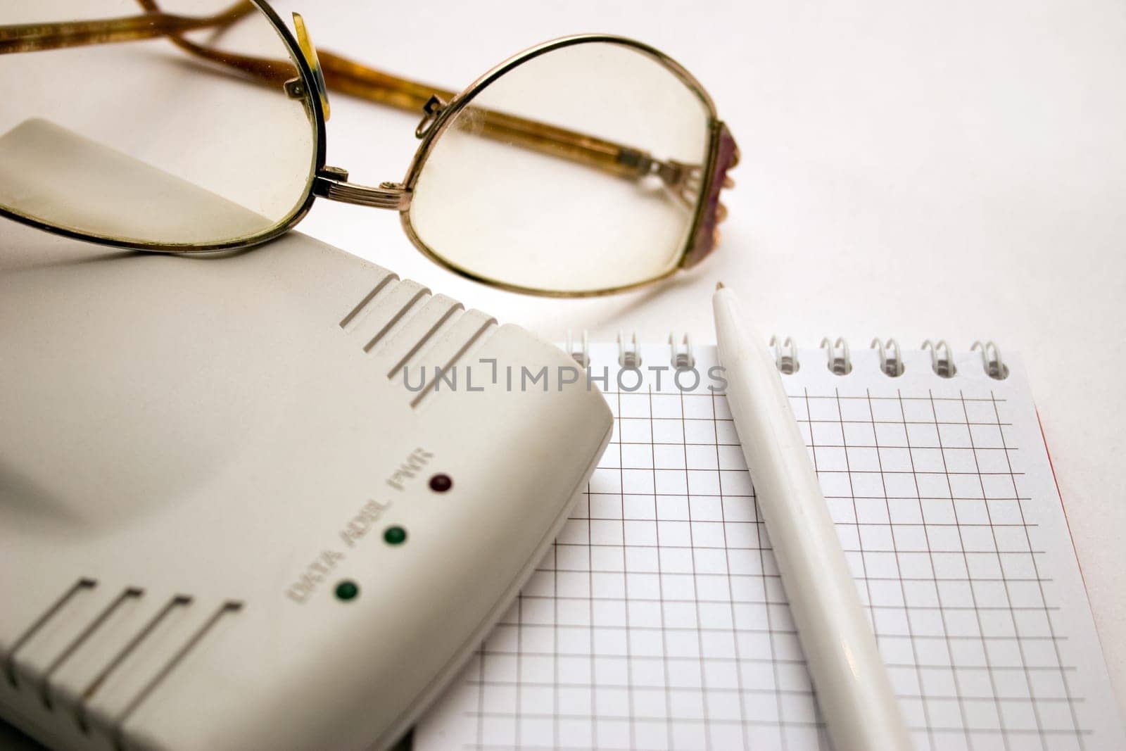 modem, notebook, pen and glasses on a light background