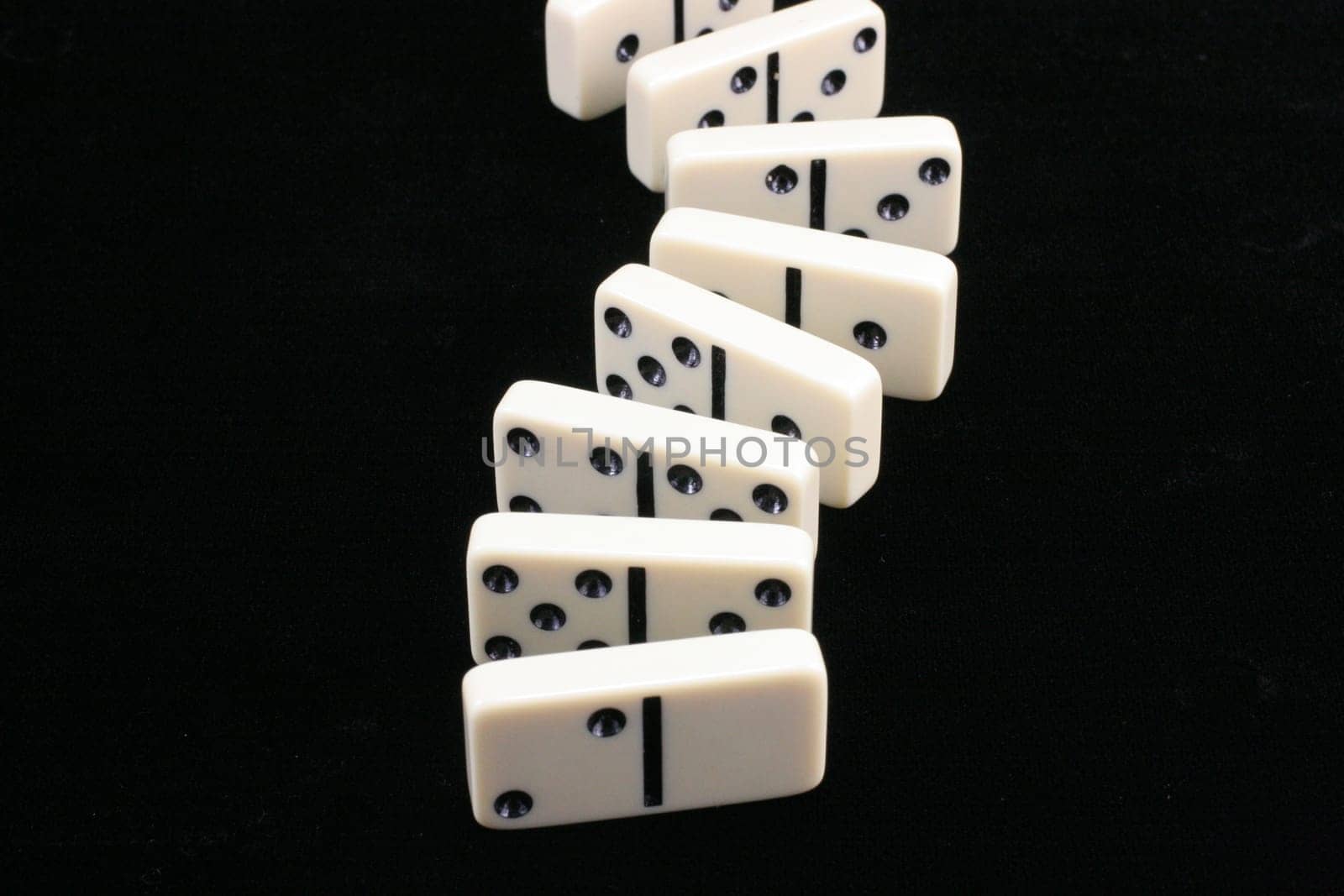 Dominos on a black background all lined up.