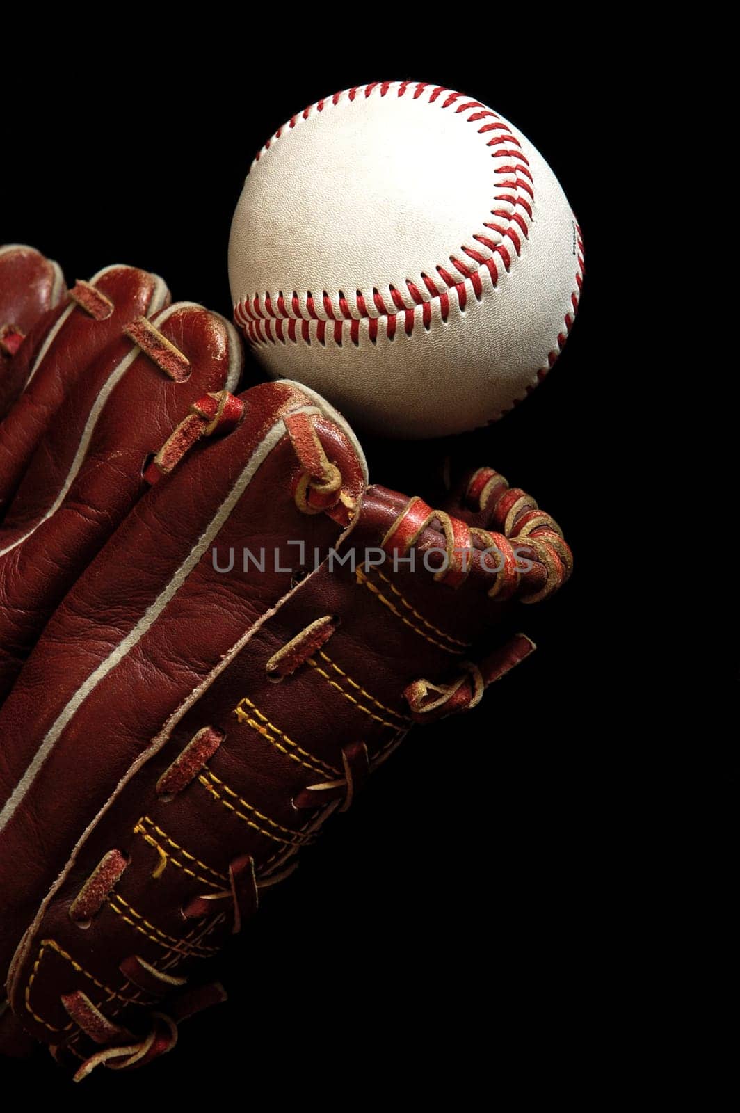 Close up of a baseball glove and a ball on a black background