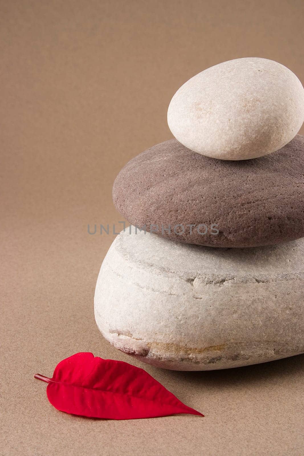 3 balanced pebbles with red and green leaves on a clear background