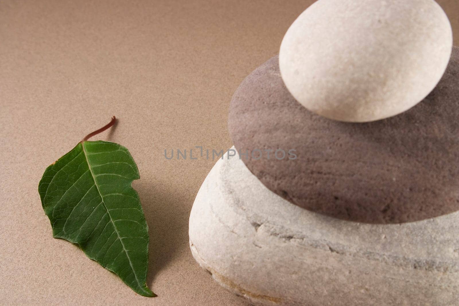 3 balanced pebbles with red and green leaves on a clear background
