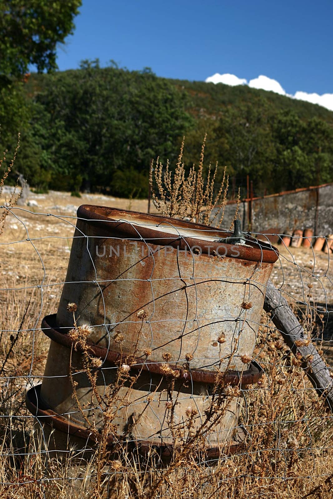 An old oil tank abandoned on the ground, leaned to the used up fencing. This is a clear sign of pollution the man should fight