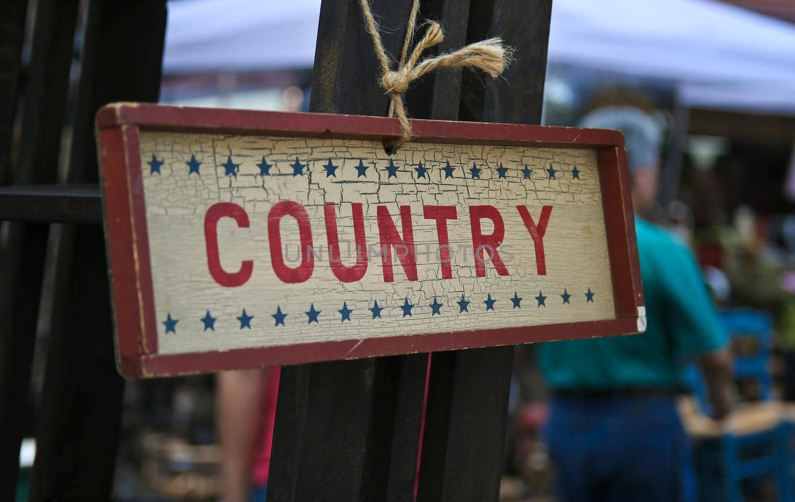 Sign hanging on a piece of string on a flea market. The sign says "COUNTRY""."