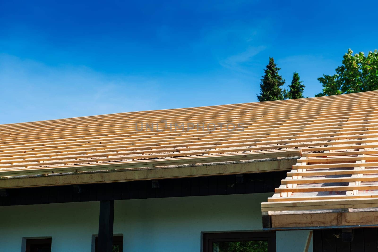 View of a roof prepared for shingles with counter battens against a blue sky.