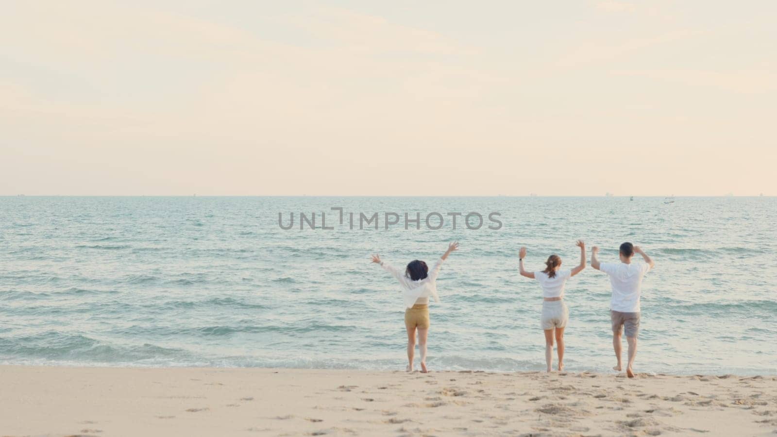 Happy friends holding hands running enjoy life funny and freedom on sand at beach together to sea in holiday vacation time at sunset, Young Asian group woman and man in summer travel, people lifestyle