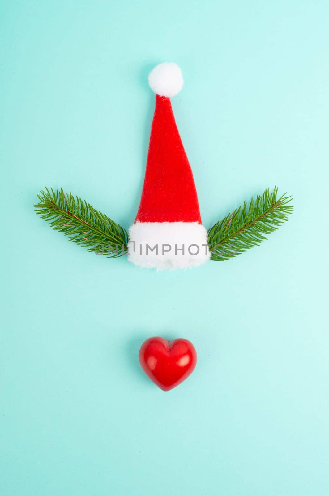 Face of a reindeer with a red heart nose, fir antlers and a santa claus hat, merry christmas greeting card