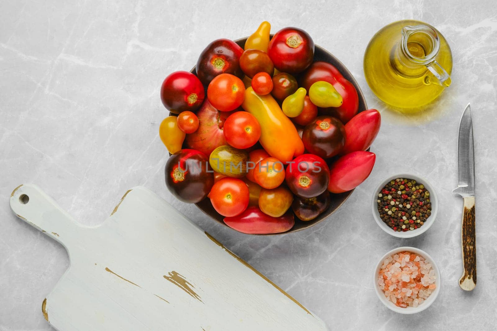 Top view of plate with colourful tomatoes, olive oil, salt and pepper. Simple vegetable salad.