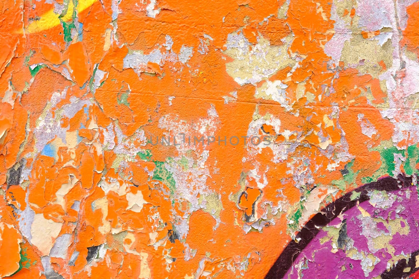 Colorful wall background with damaged paints of orange.