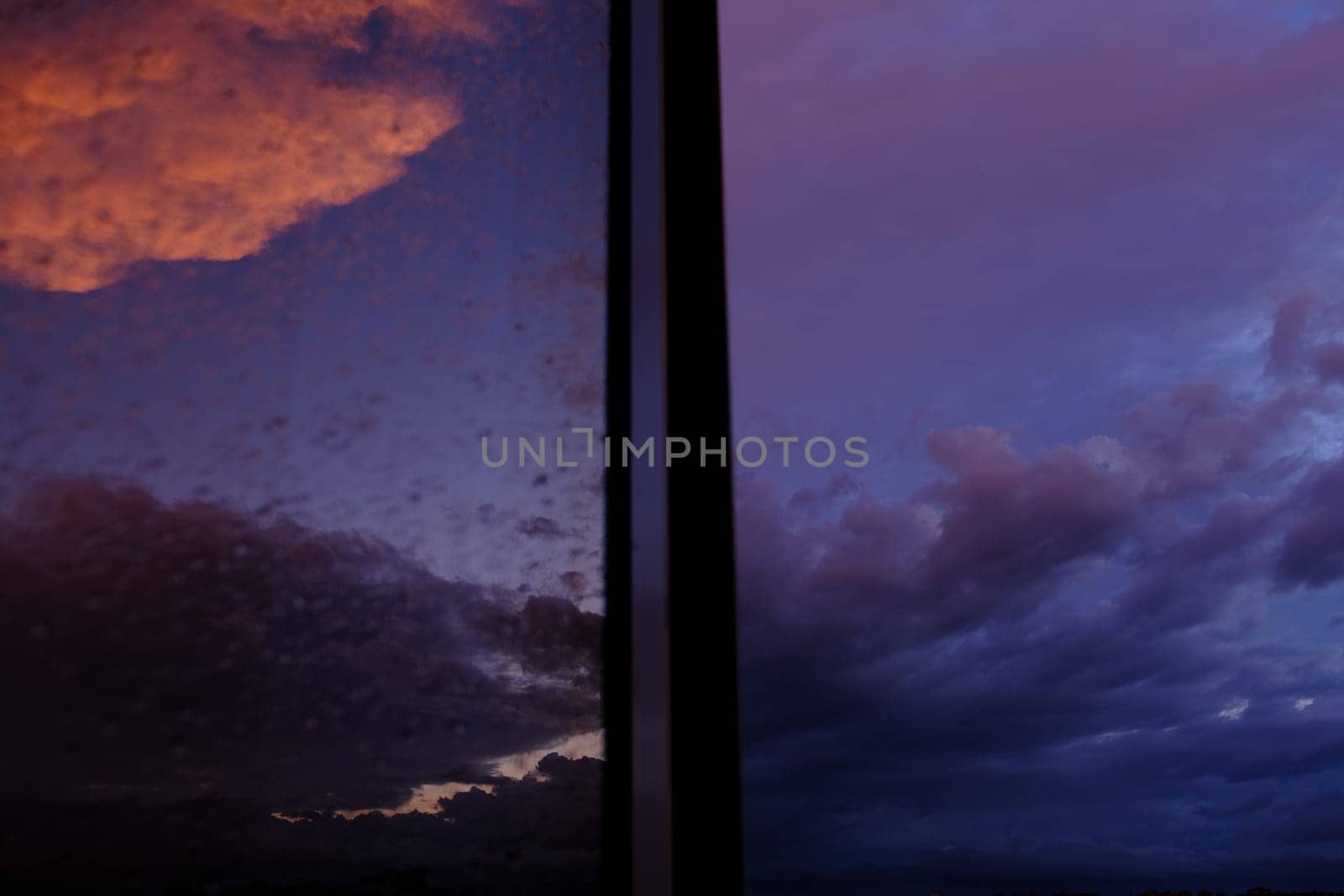Dawn sky with colorfull clouds. Sunset landscape through the window with reflection on it.