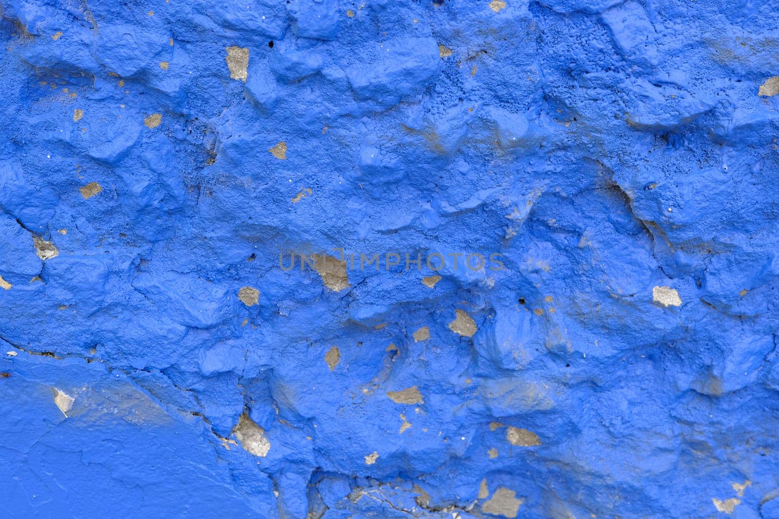 Colorful wall background with damaged paints of blue.
