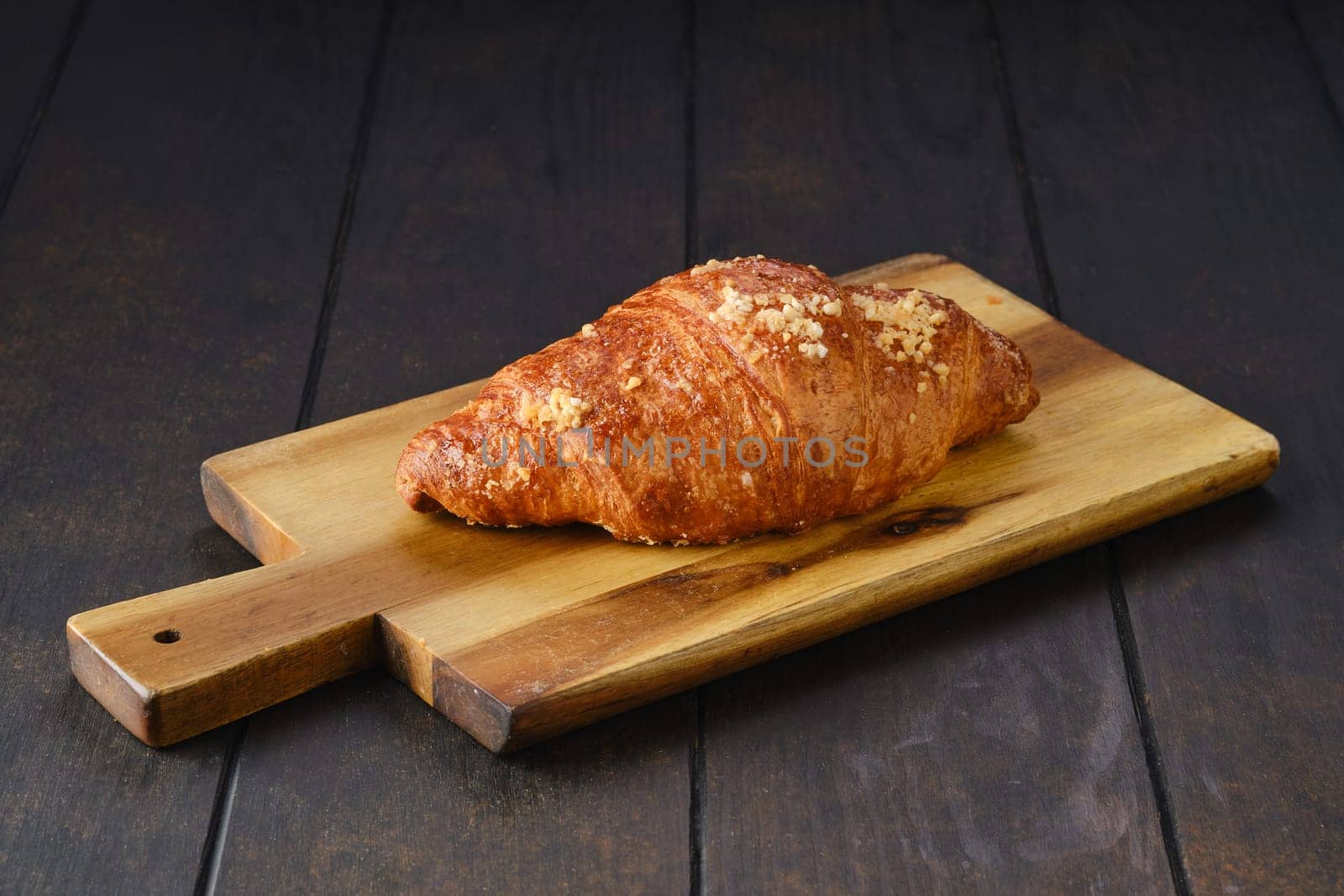 Classic croissant on wooden serving board.