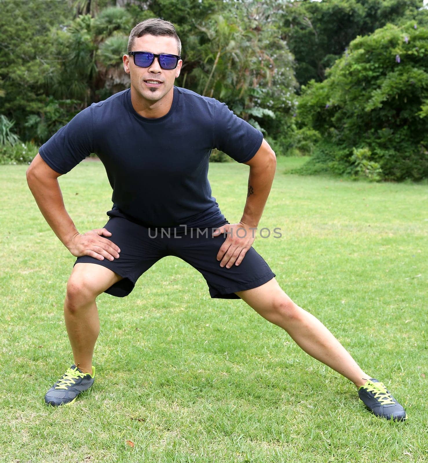 Handsome young man doing stretching exercises outdoors