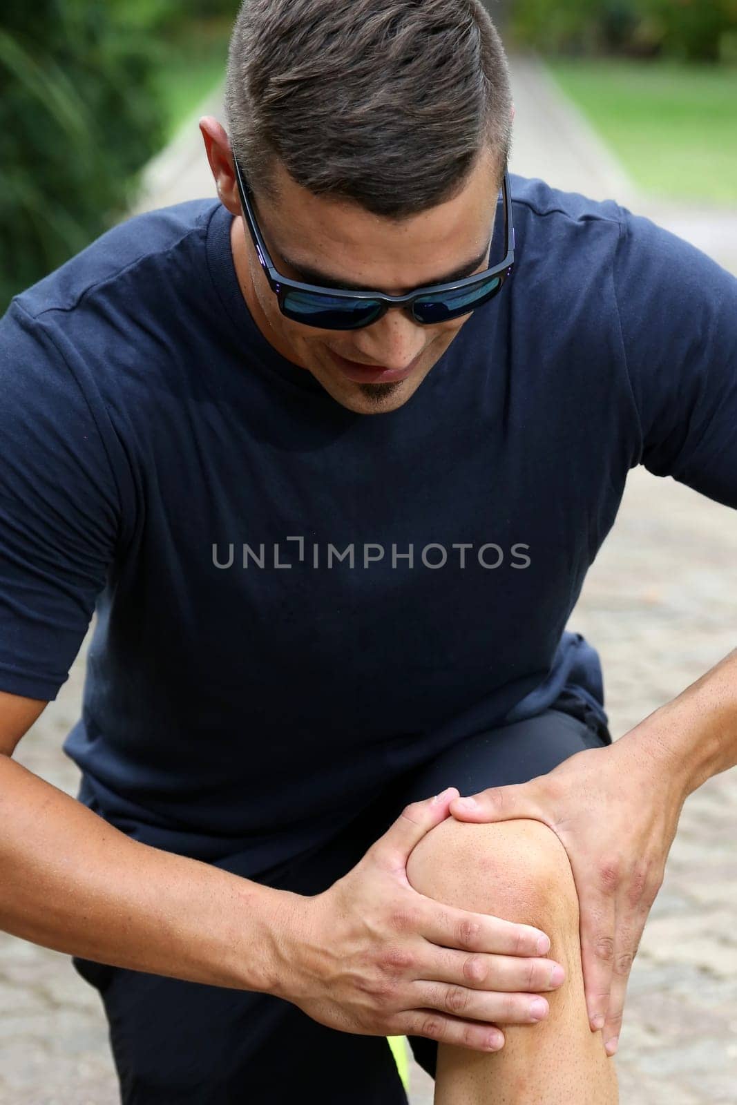Handsome young athlectic man inspecting his sore knee