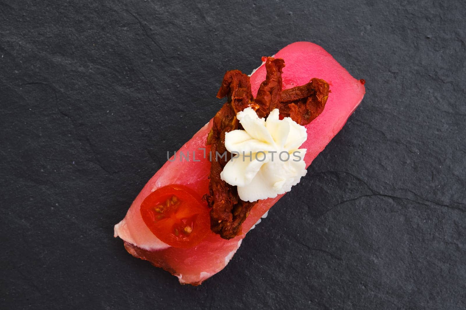Sushi with tuna, dried tomato and cream cheese on slate plate