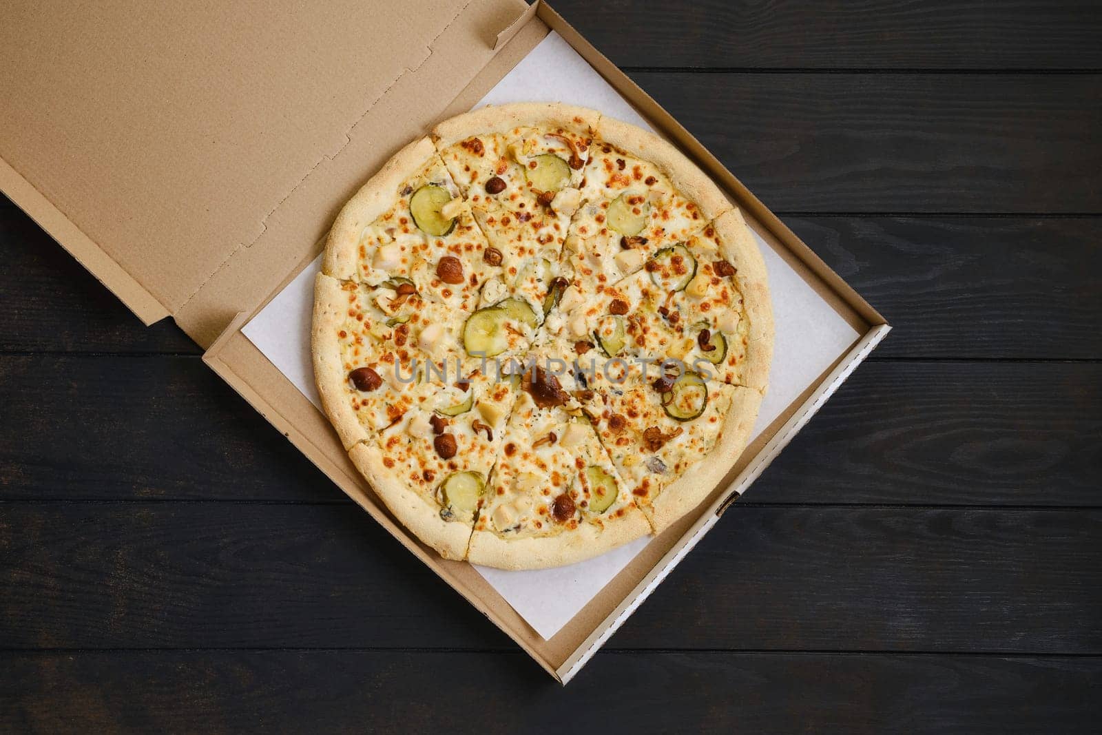 Pizza with chicken, honey mushrooms and pickled cucumber in cardboard package