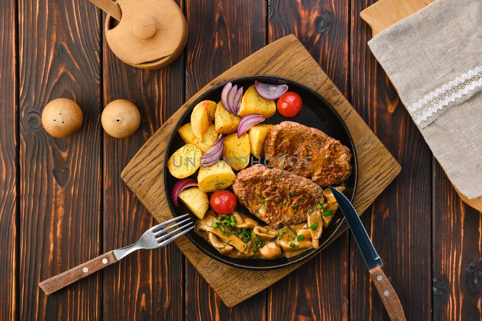Plate with fried pork fillet, potato wedges, mushrooms and tomato