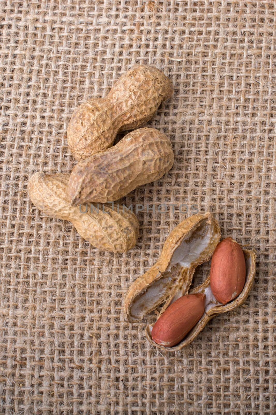 Cracked open peanuts with shell on a linen canvas background
