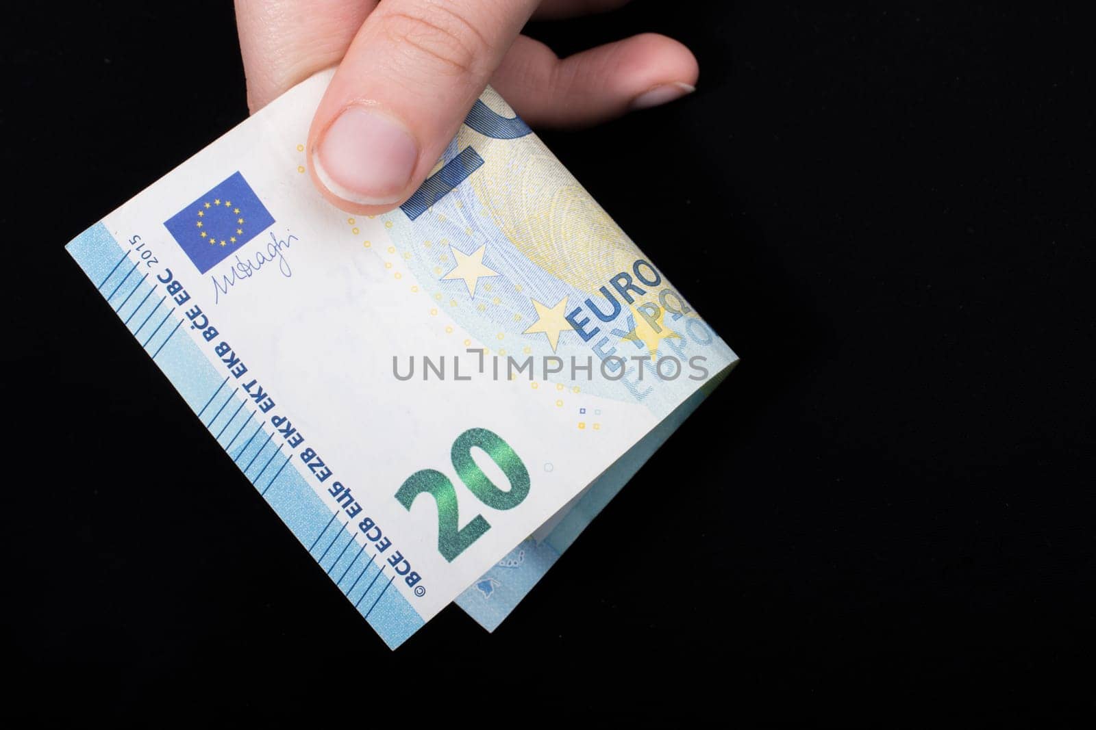Hand holding 100 euro money  cash isolated on black background